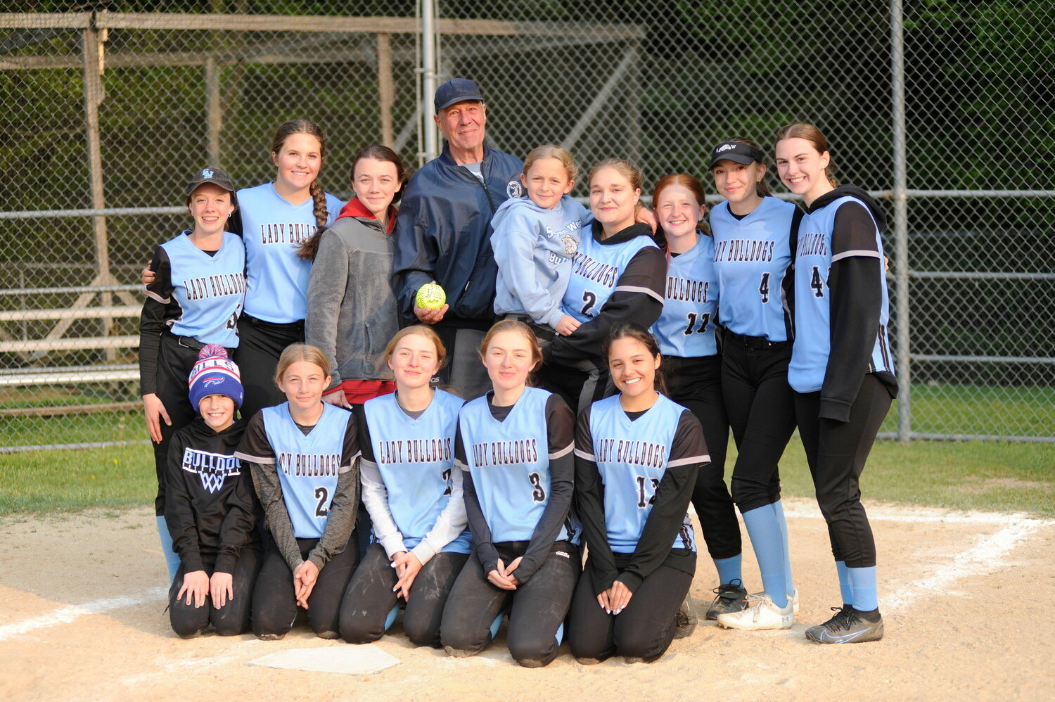 On May 17, after the second out in the final frame of Sullivan West’s game against Port Jervis, the game was halted so the Lady Bulldogs could present retiring NYSSO official Dan Clark with a signed ball. He is pictured with the team. Front row: Allie Hellerer, left; Kierston Knapp; Liz Reeves; Nicole Reeves; and Georgeanne Cardona. Back row: Sam Hellerer, left; Karlee Diehl; Hannah Abplanalp; home plate ump Dan Clark; Kenzie Knapp; Lucy Arzill; Cheyenne Decker; Kaitlyn Drobysh; and Paige Muzuruk...
